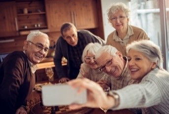 Gruppe von älteren Menschen in geselliger Atmosphäre macht ein Selfie mit einem Smartphone